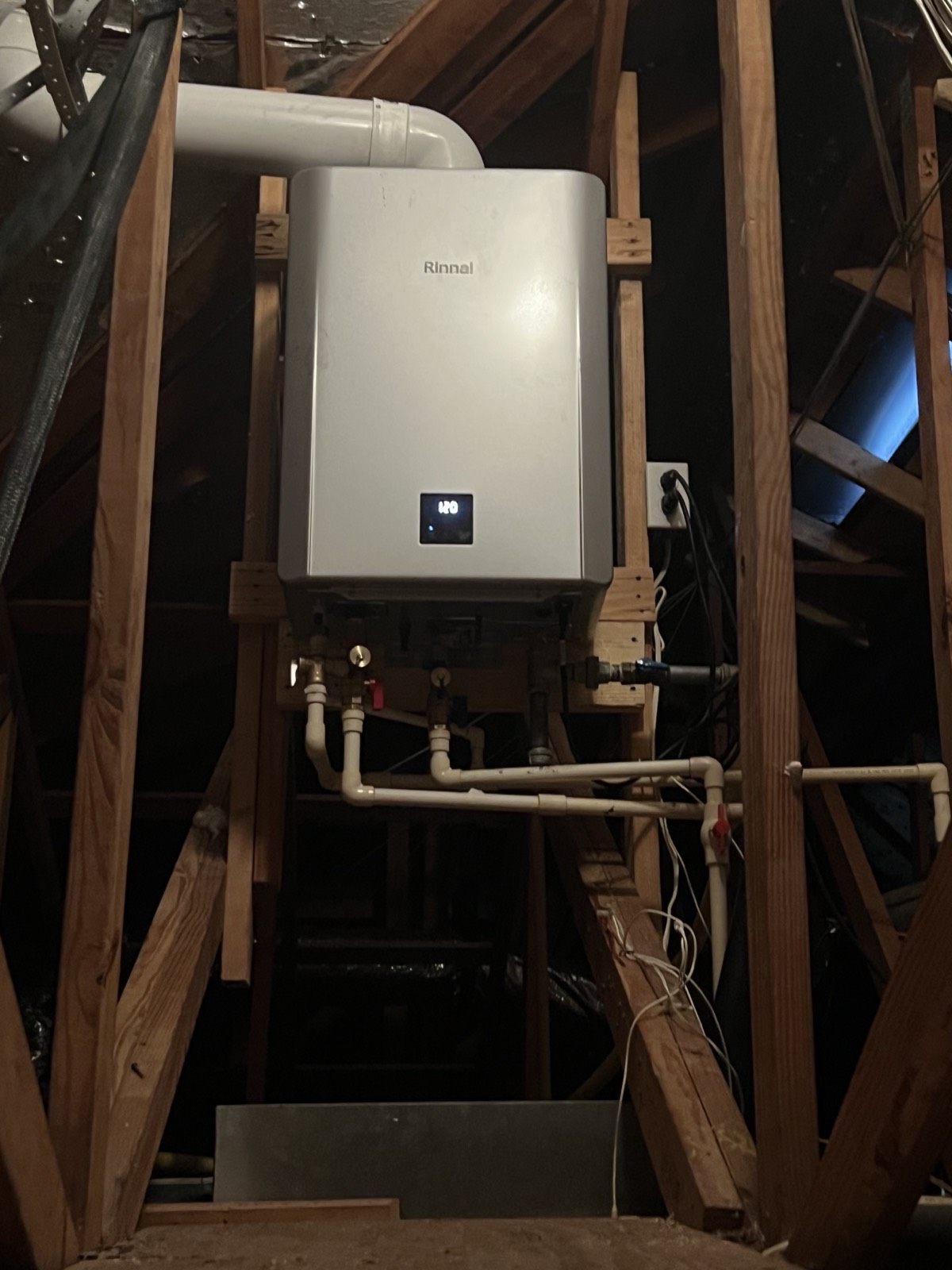 Rinnai tankless water heater installed in an attic with neat PVC venting and copper supply lines