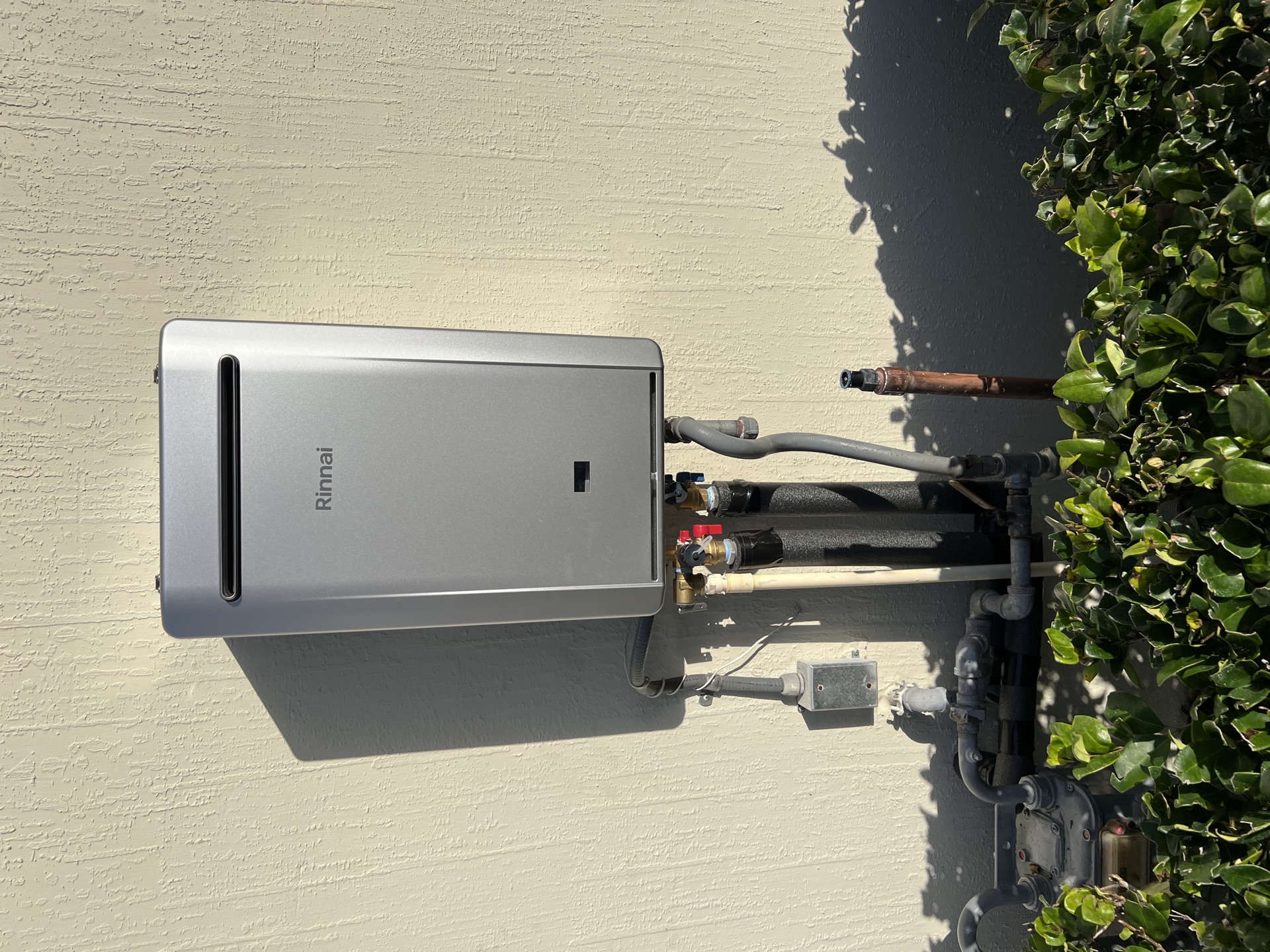 Rinnai tankless water heater installed on the side of a Nassau County home with proper isolation kit